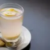 Segelas air hangat dengan perasan lemon di atas meja