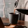 secangkir kopi hitam di atas meja kayu
