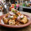 Tahu gejrot Cirebon di atas piring gerabah dengan kuah sambal dan irisan bawang